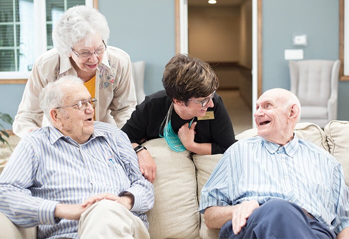 Senior living residents having a conversation and smiling with staff memeber