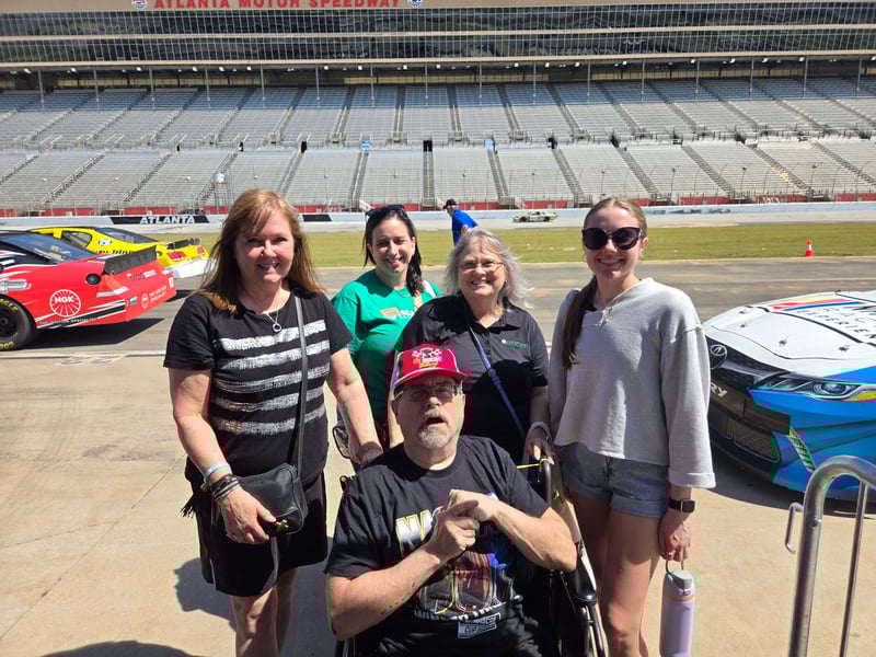Mark Saul poses for a photo with his family on at Atlanta Motor Speedway, just before riding in a Nascar racecar at 170 mph.