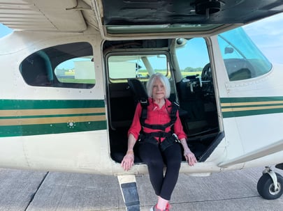 Charlotte sits in the passenger's seat of a plane parked on a runway, just before going skydiving.