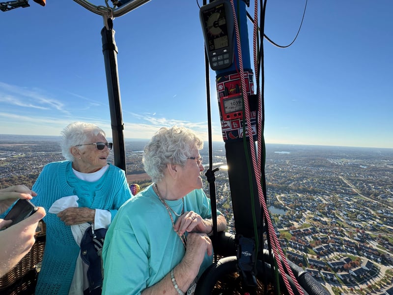 Cedarhurst Senior Living residents Leona Lewis and Carolyn Hollander are standing in a hot air balloon, gazing out at the St. Charles county suburbs from high above the ground.
