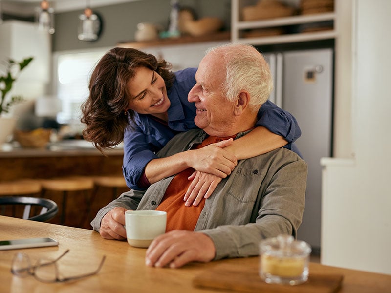 Lovely adult daughter embracing senior father from beahid