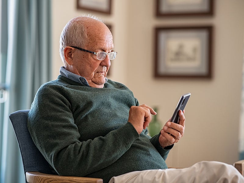 Senior man using smartphone at home
