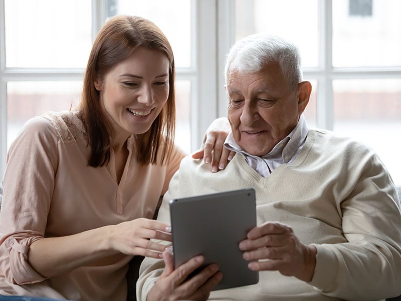 A senior man with her daughter using a tablet