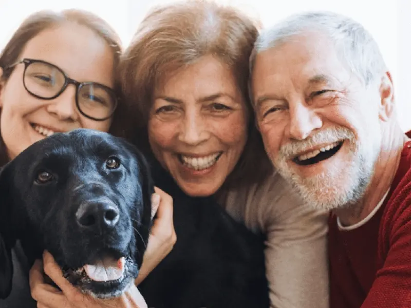 Smiling family trio with a black Labrador