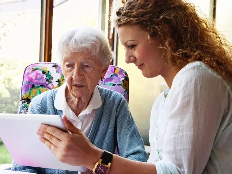 A woman holding a tablet for a senior