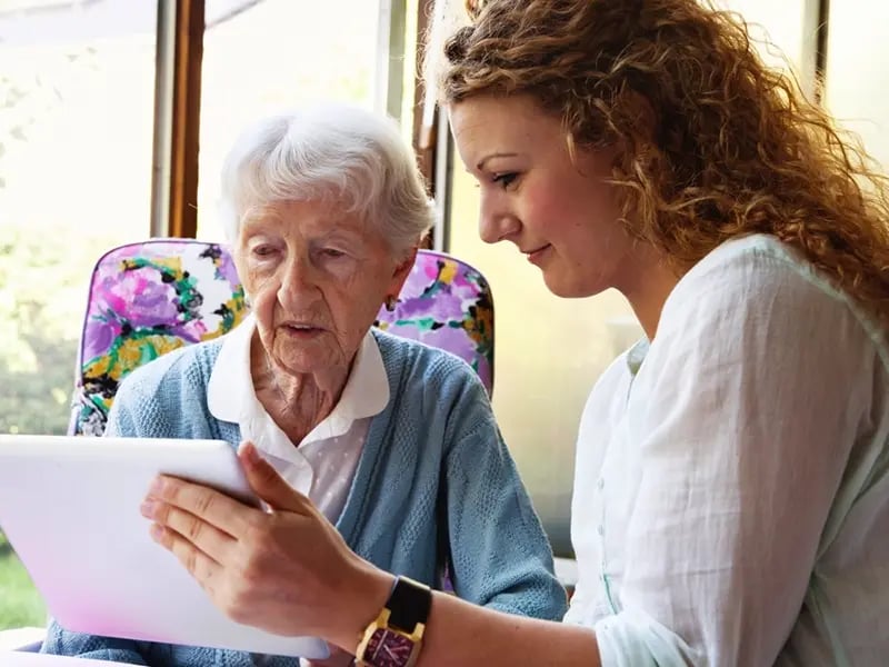 A woman holding a tablet for a senior