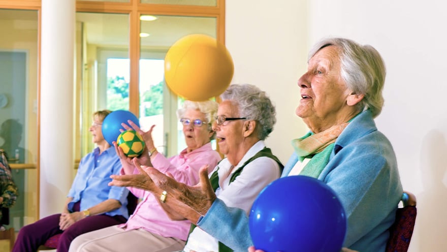 Senior living residents exercising together with colorful balls