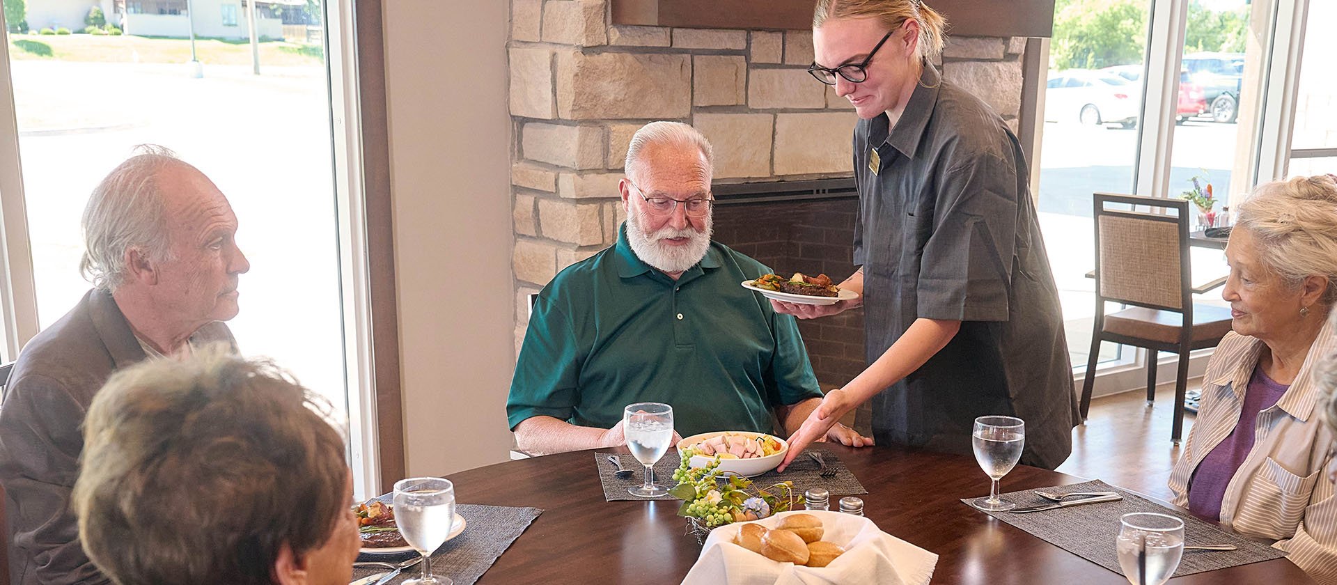 Cedarhurst dining team member serving lunch to a table of residents