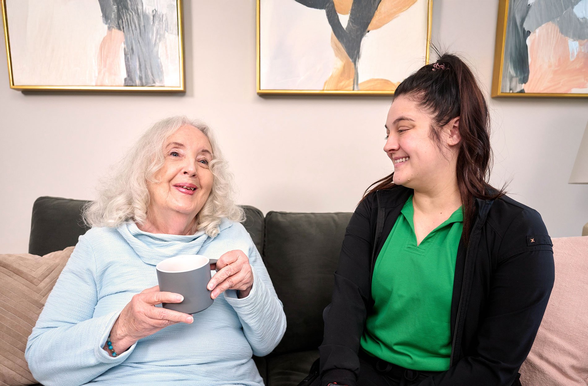 senior woman in assisted living home sitting on the couch with caretaker