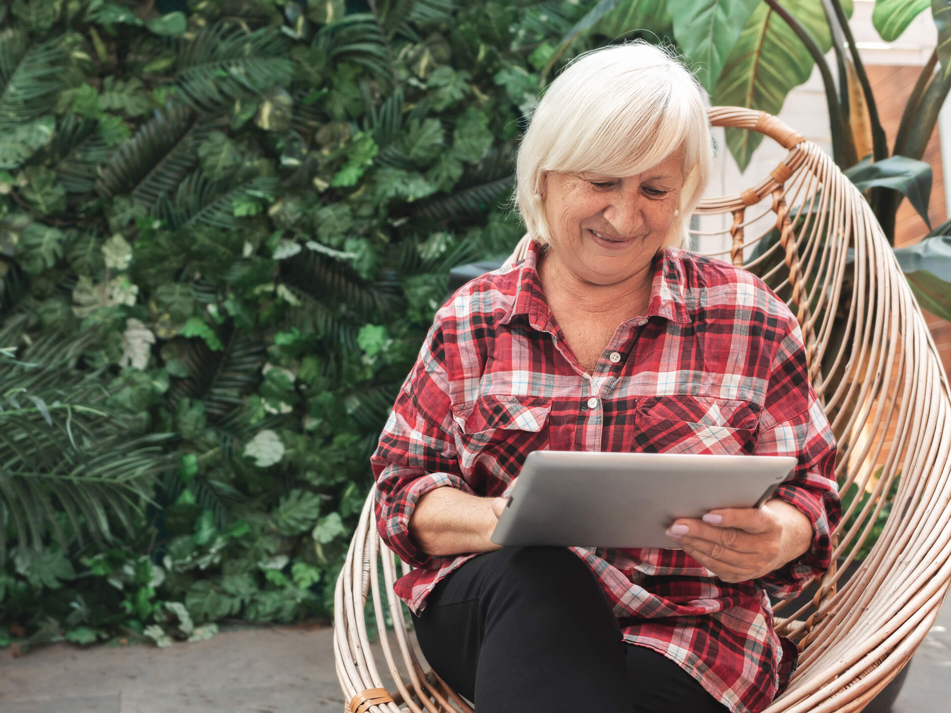 senior woman sitting on outdoor patio using tablet