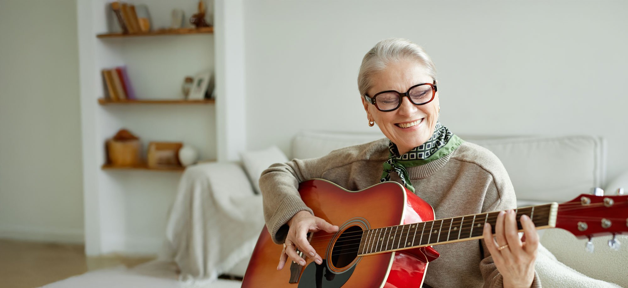 senior woman playing guitar in living room