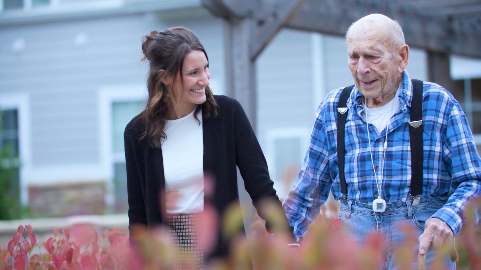 Staff member walking outside with senior man