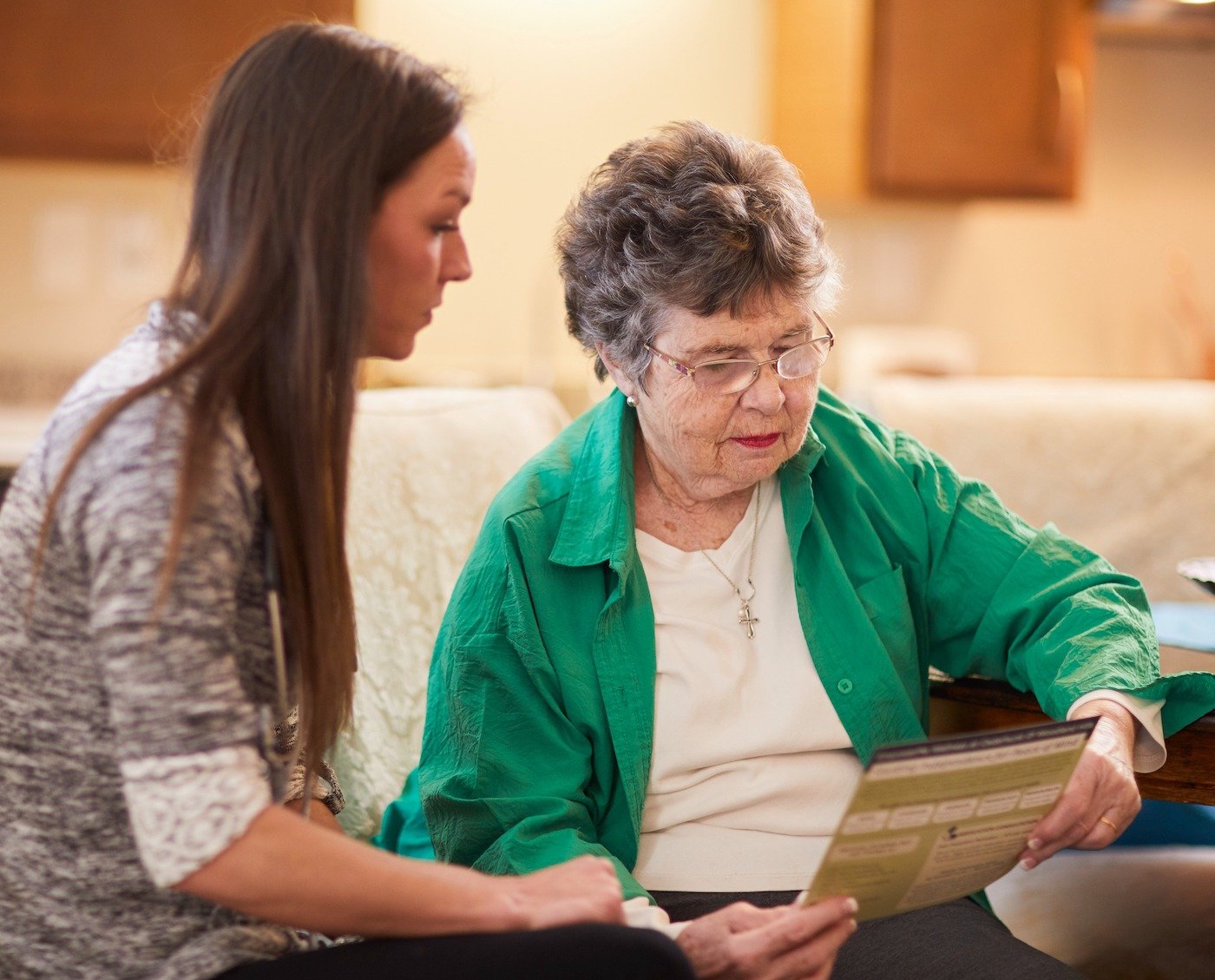 A senior woman reading with a young woman