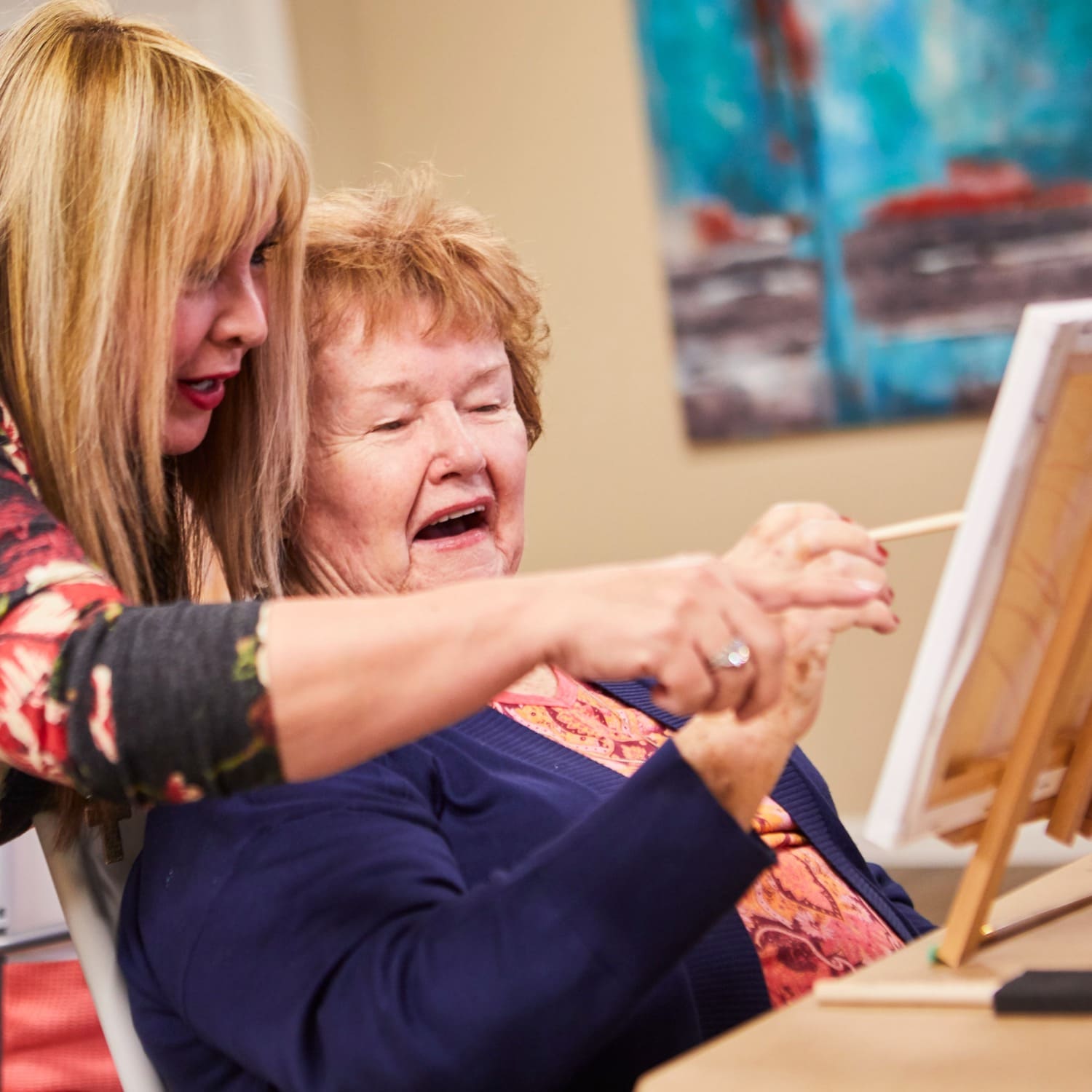 Caregiver helping senior woman during a painting class