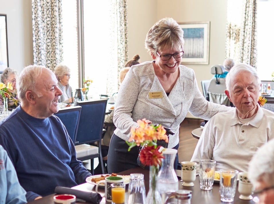 A staff member serving coffee to senior residents in the restaurant