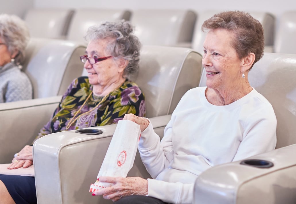Senior ladies watching a movie and eating popcorn