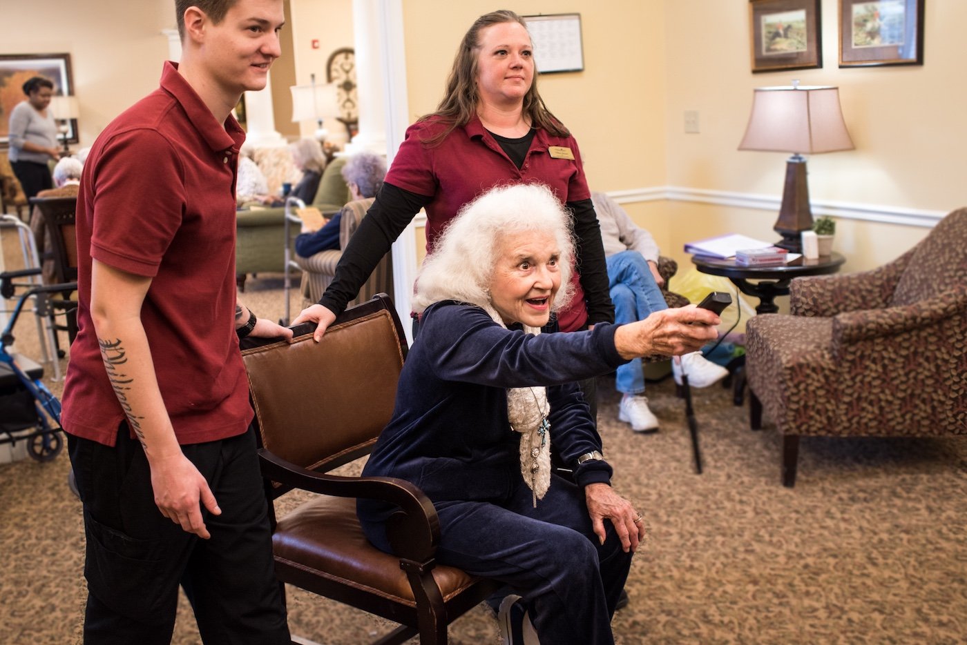 Senior woman playing video games with staff members