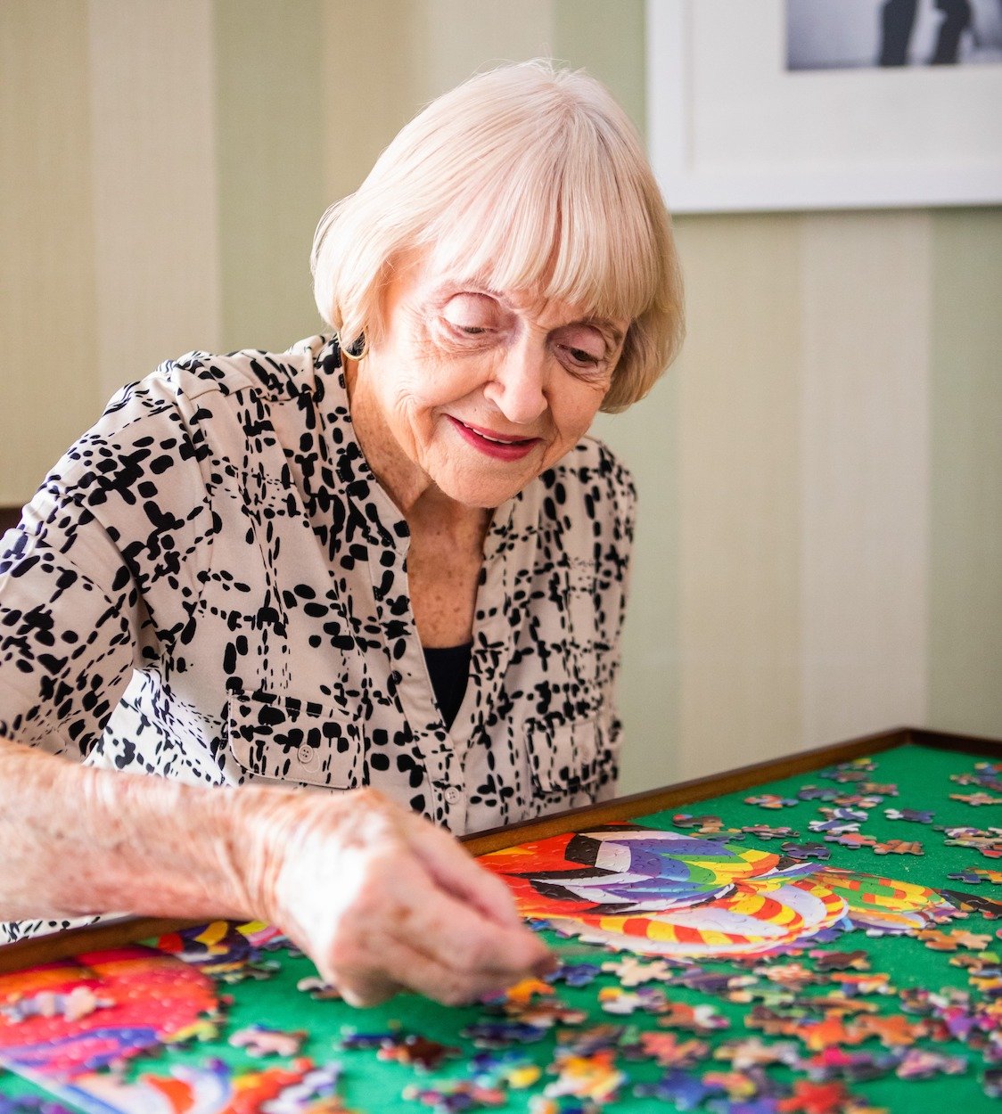 Senior woman completing a jigsaw puzzle at a table