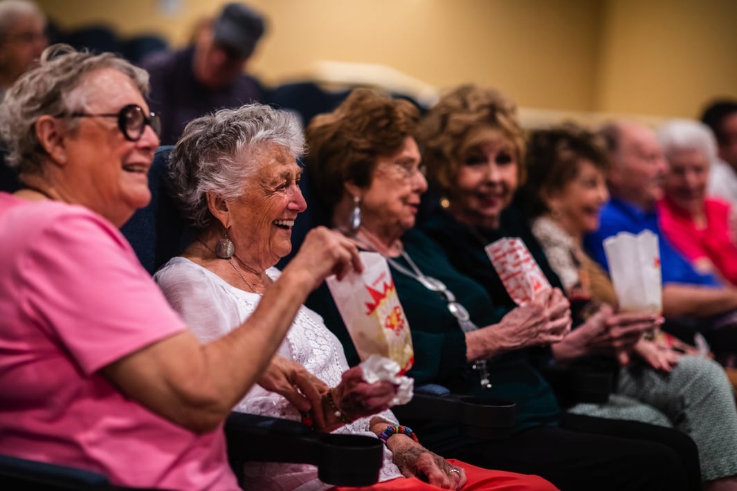 A group of senior women watching a movie and eating popcorn
