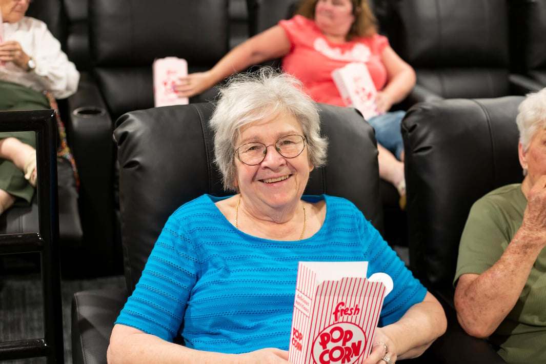 Resident holding popcorn box in the community movie theater