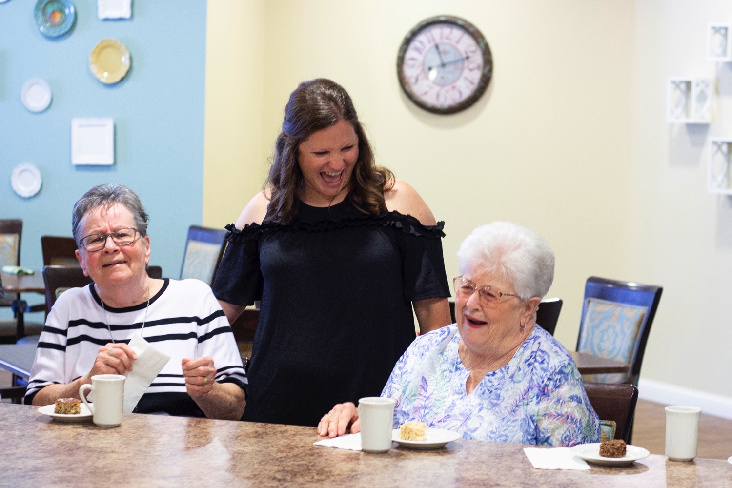 Cargiver Serving a Meal and Laughing with Residents in the dining room