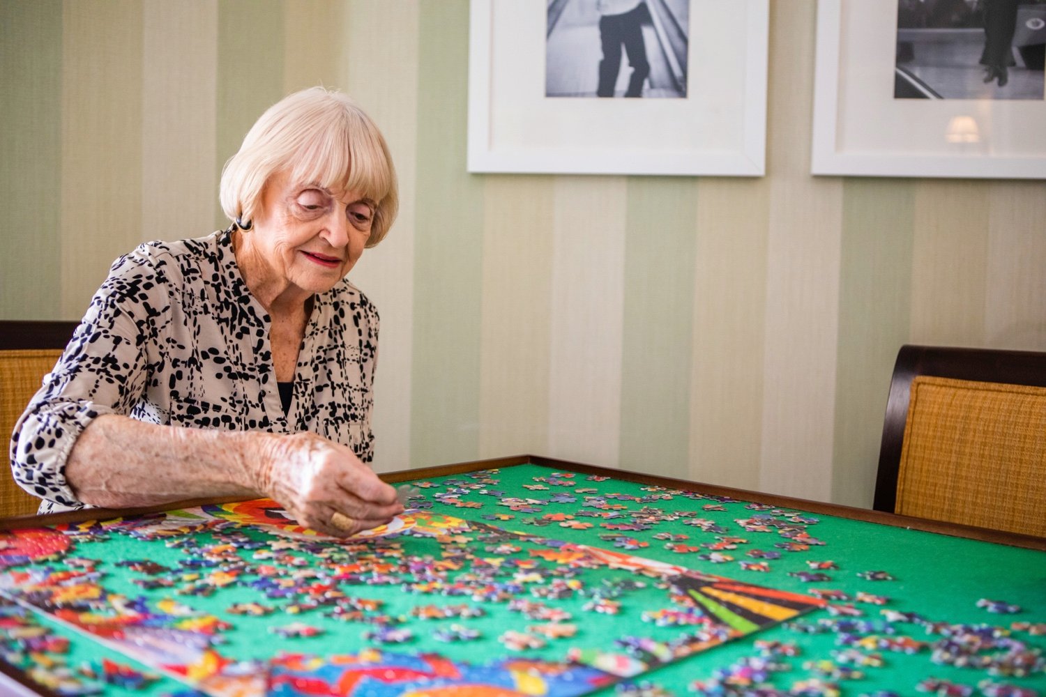 Senior woman seated at a table and working on a jigsaw puzzle
