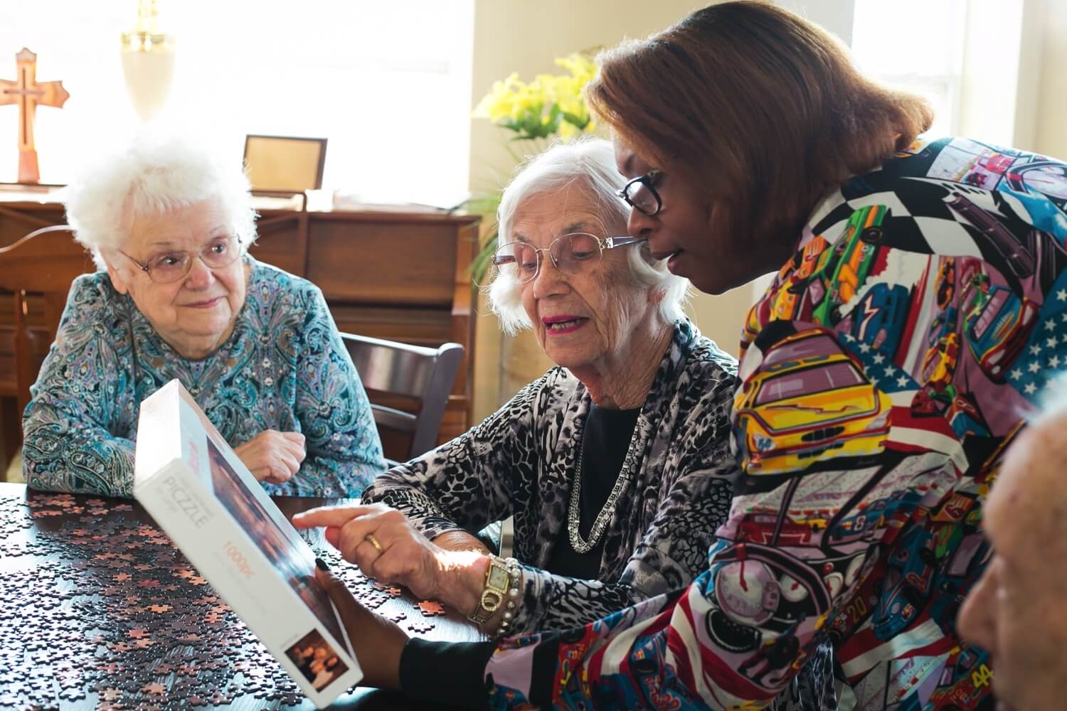 A staff member helping two senior residents with a jigsaw puzzle