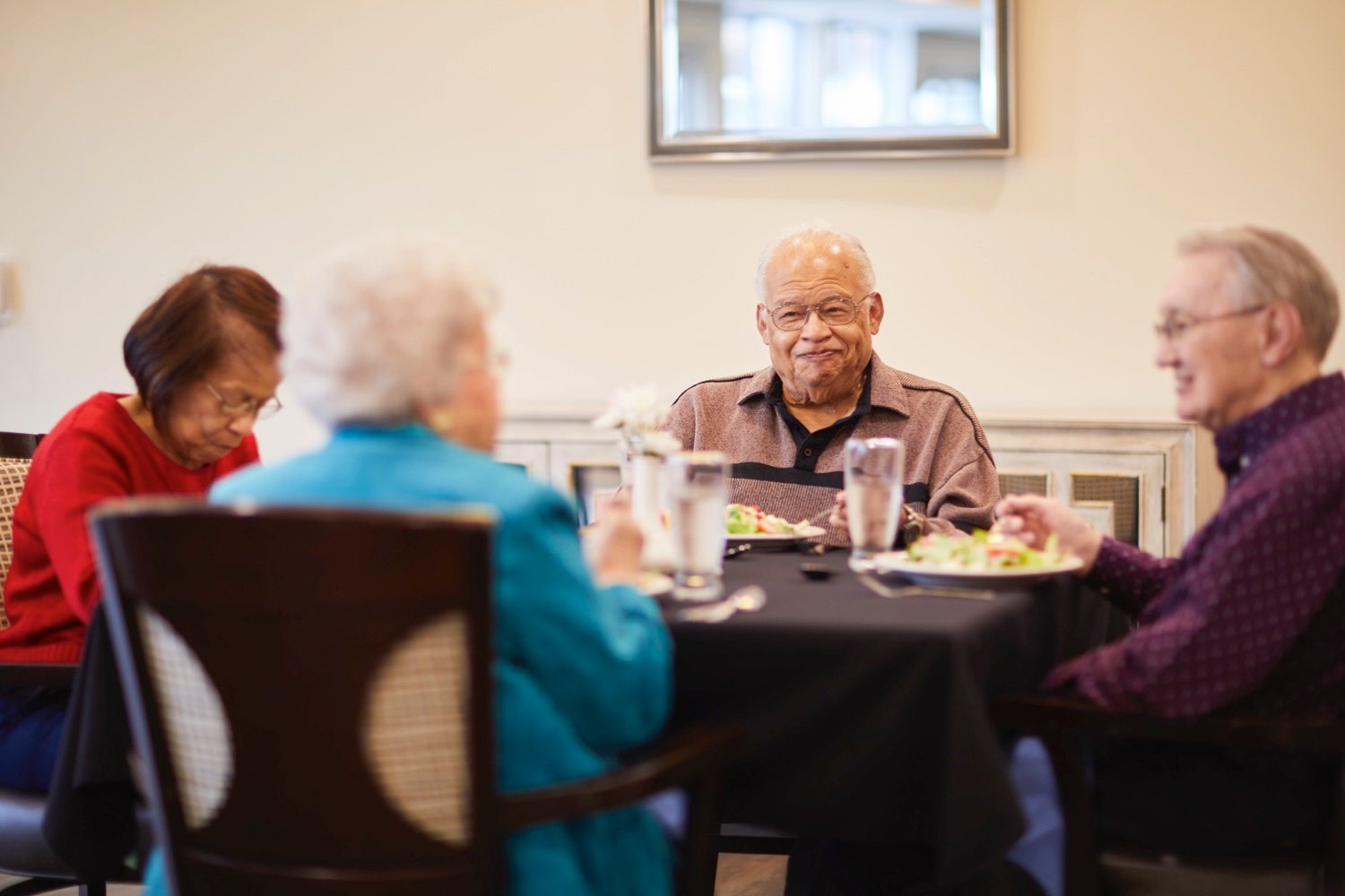 A senior resident enjoying a meal with friends in the community restaurant
