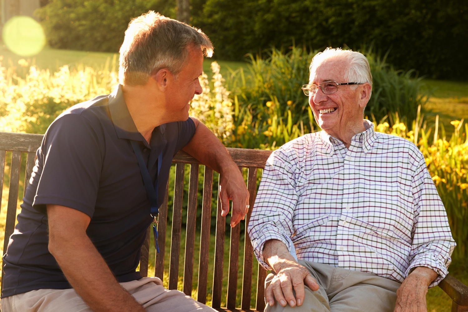 Staff member talking with senior on a park bench