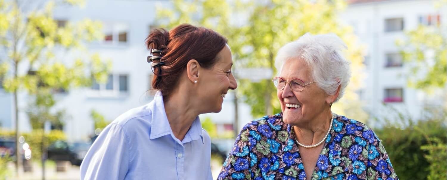 Staff member helping senior with walker outdoors