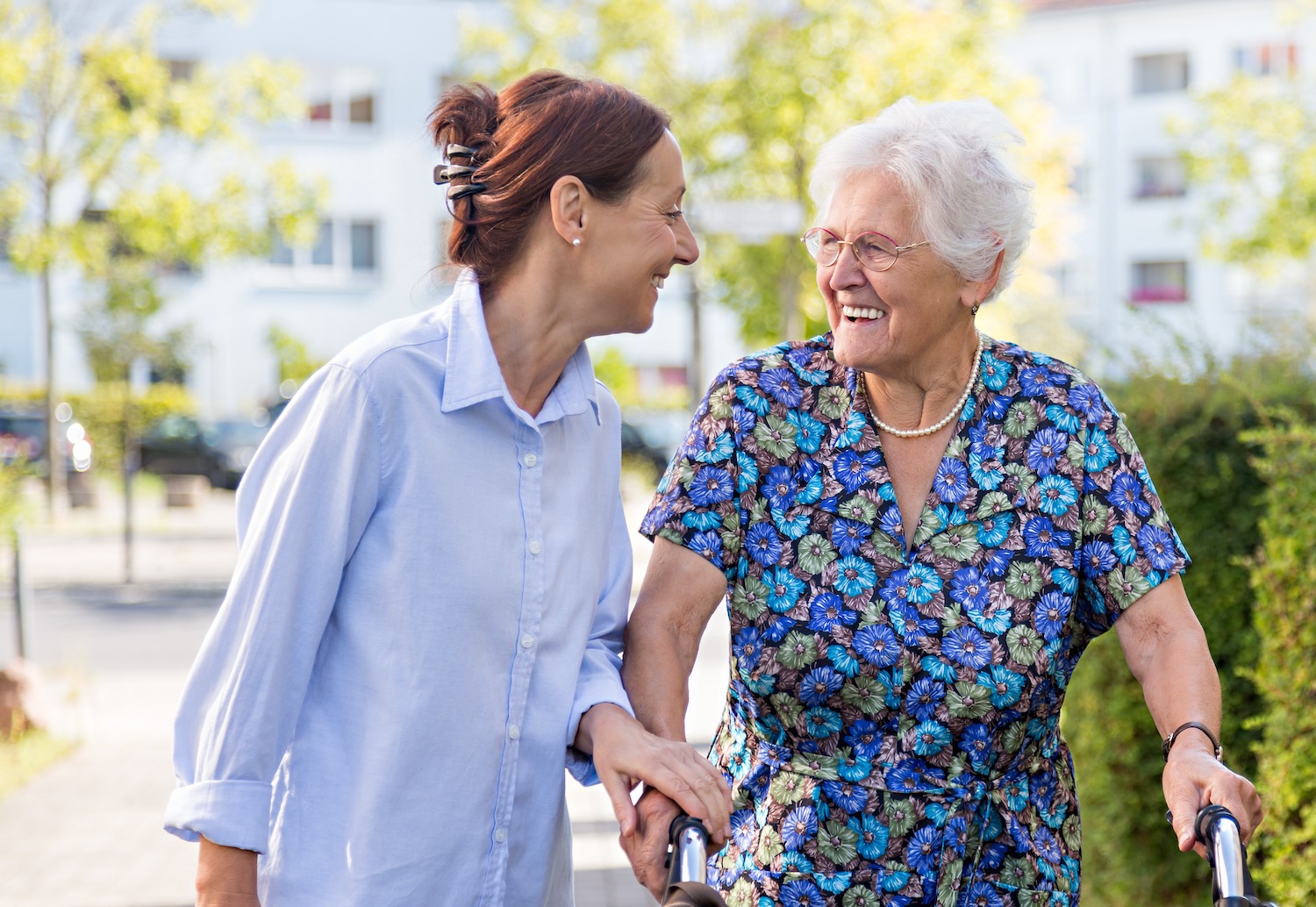 A team member helping a senior woman with a walker in the community garden