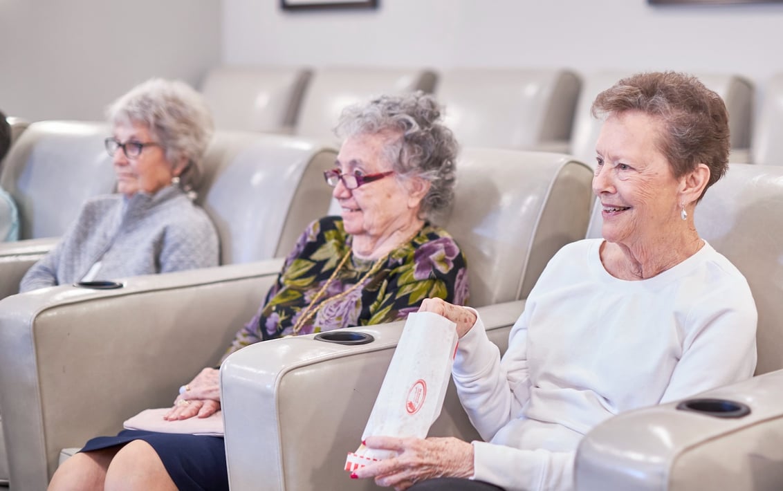 Senior residents watching a movie and eating popcorn in a community theater