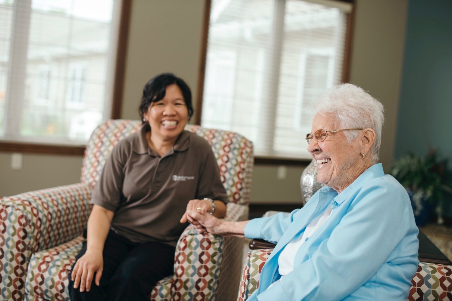 Cedarhurst staff member holding hands with a resident as they sit side-by-side