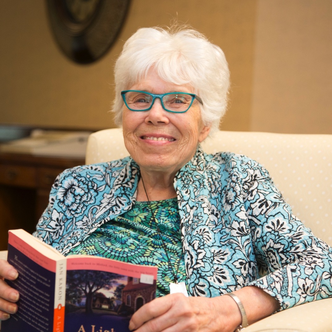 Resident smiling and reading in a chair