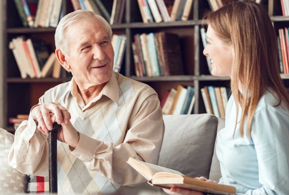 Father and daughter at home library sitting man looking at woman holding book laughing