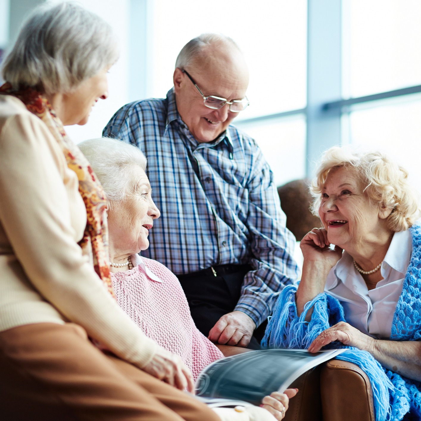 Four senior friends talking and reading a magazine