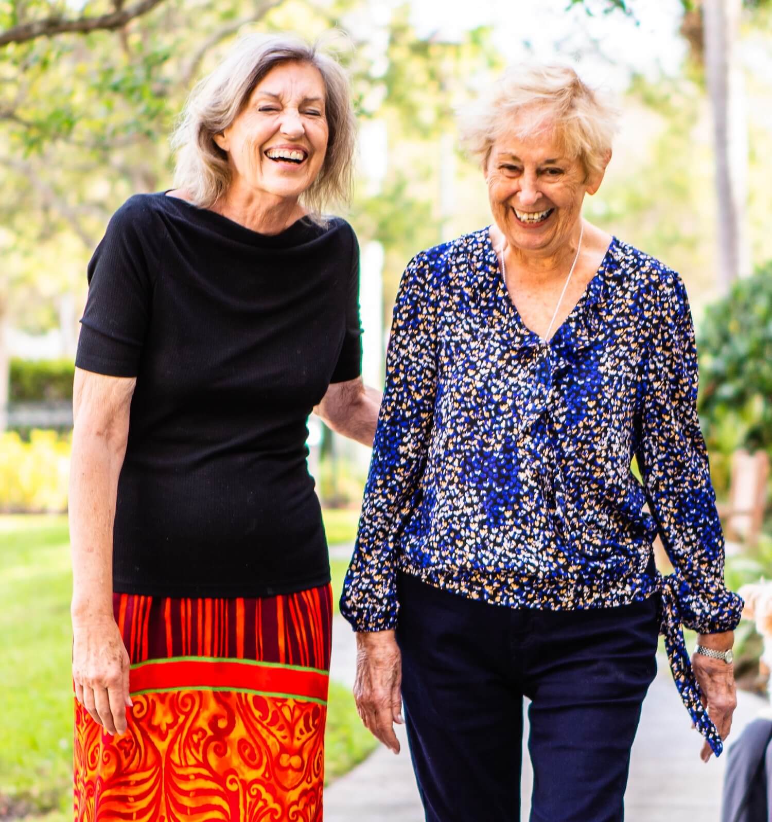 Two senior women walking on a garden path
