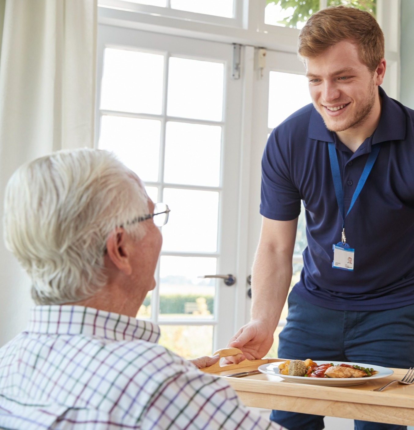 Staff member bringing food to senior man