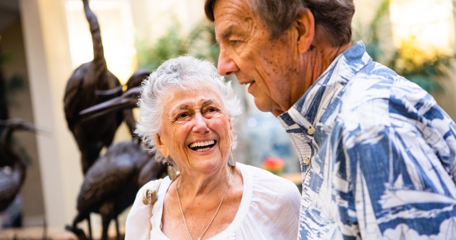 Two seniors laughing together in the atrium