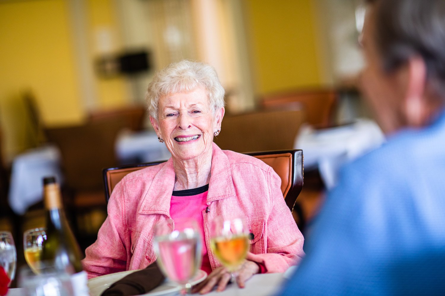 Senior woman smiling at the camera while seated with friends in the community restaurant