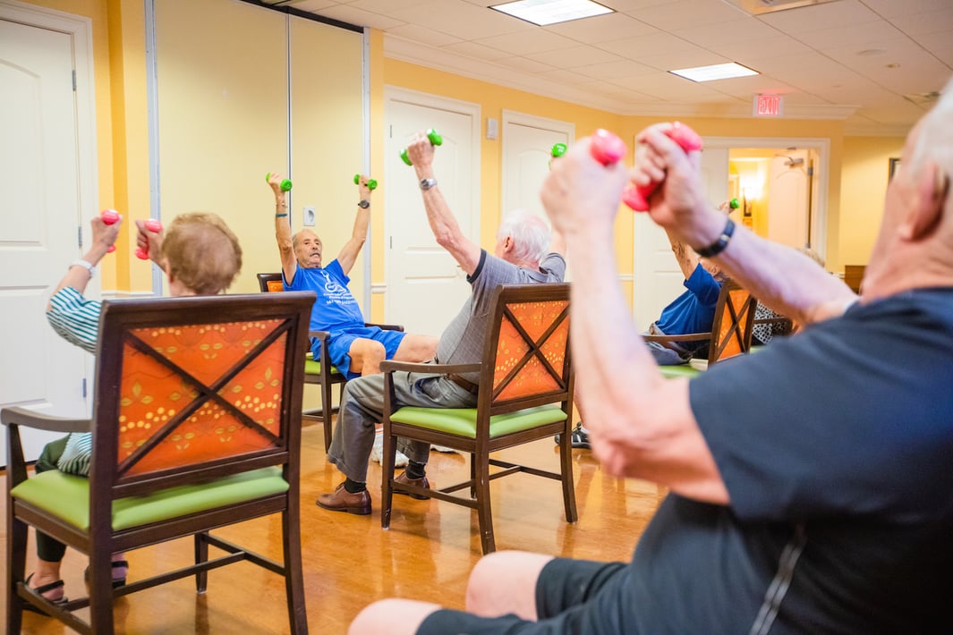 Group of seniors participating in a seated exercise class with handweights