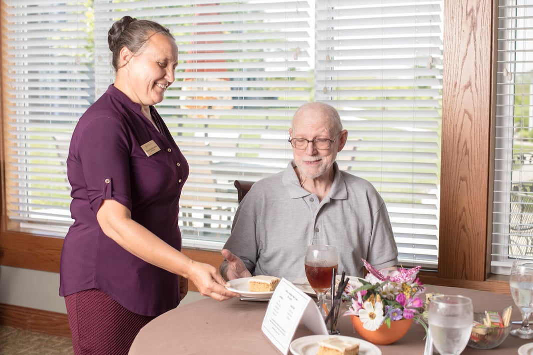A team member serving dessert to a resident in the community restaurant
