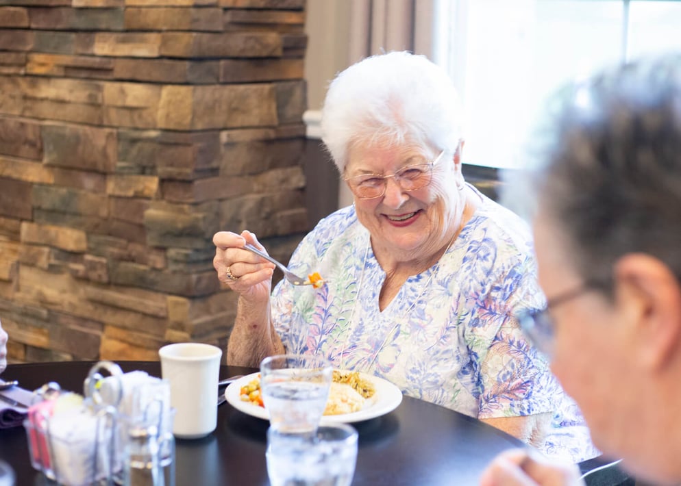 Senior woman eating in the community dining room