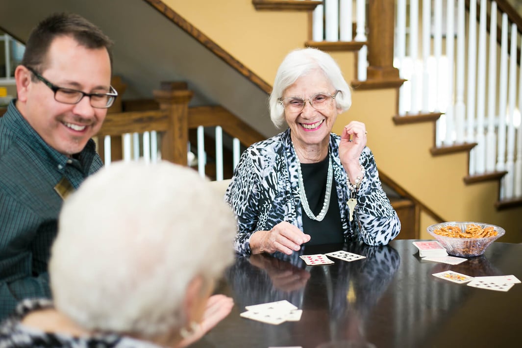 Senior women playing cards with a team member