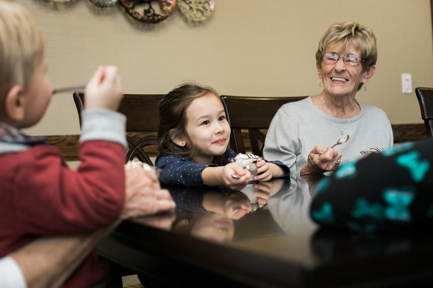 A senior woman eating ice cream at a table with her grandchildren
