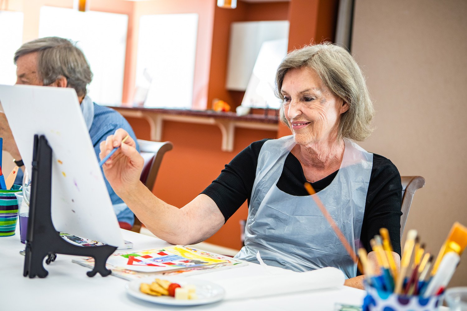 Senior woman smiling as she participates in a painting class