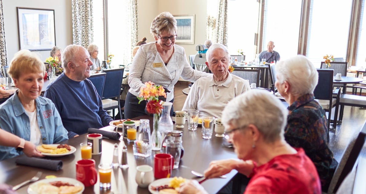 A staff member serves coffee to senior residents at lunch in the community restaurant