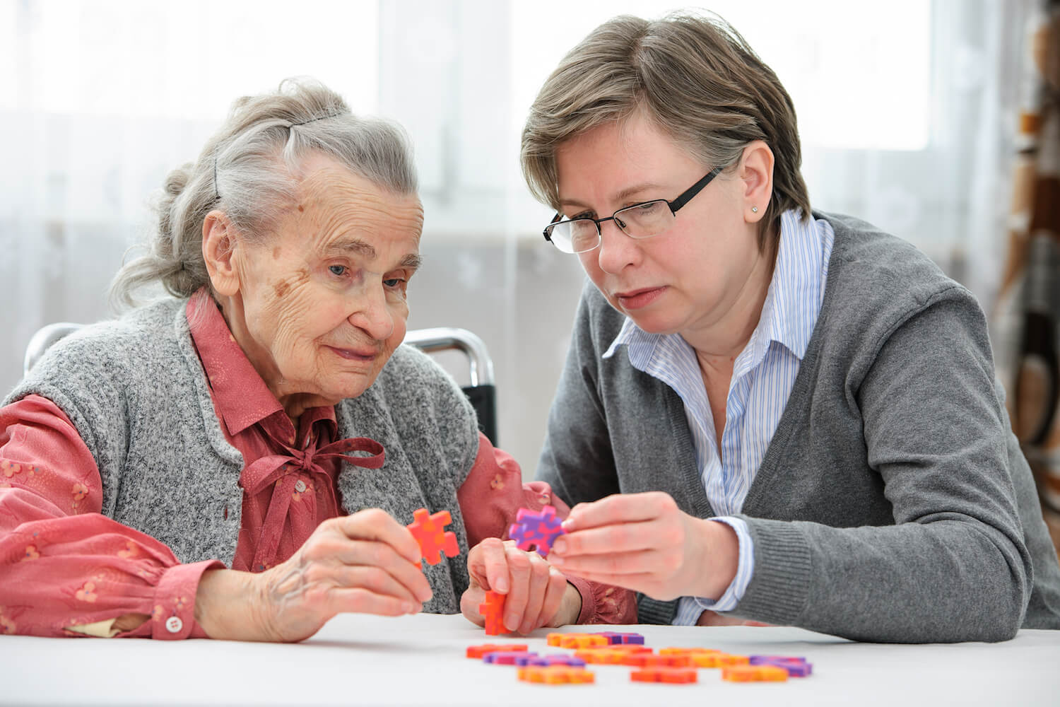 Senior woman building a puzzle with staff member