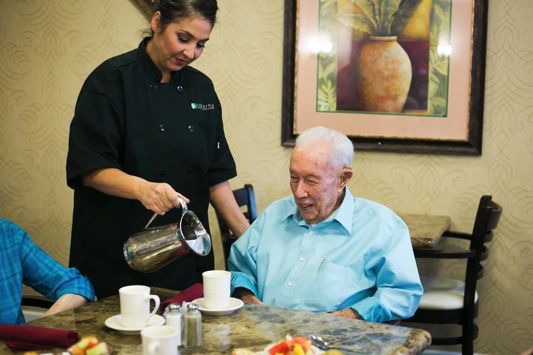 Senior man being served food by staff member