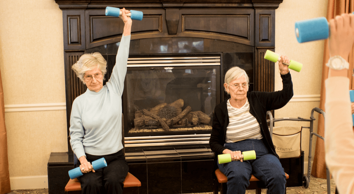 Senior residents participating in a seated exercise class with hand weights